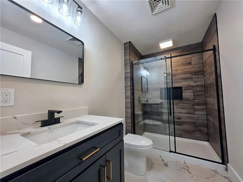 Finished Greenhurst bathroom with a glass shower and dark vanity