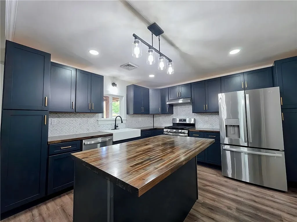 Renovated Greenhurst kitchen with navy cabinetry and a wood island